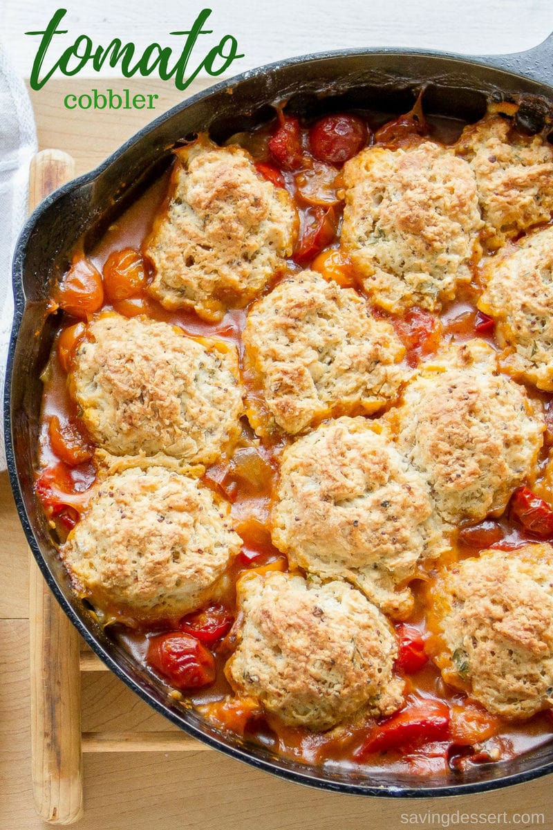 A cast iron skillet filled with savory tomato cobbler with herbed biscuit topping