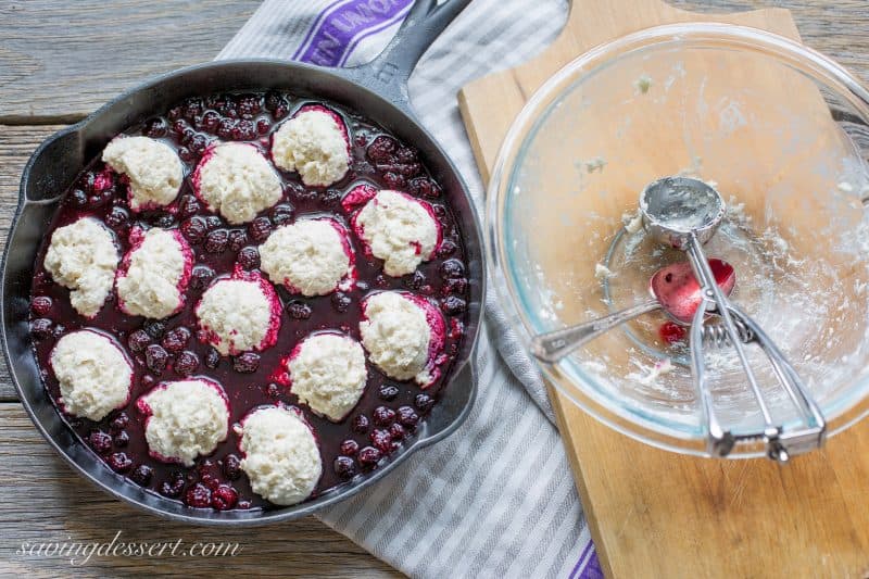 An unbaked black raspberry cobbler in a cast iron skillet with biscuits on top