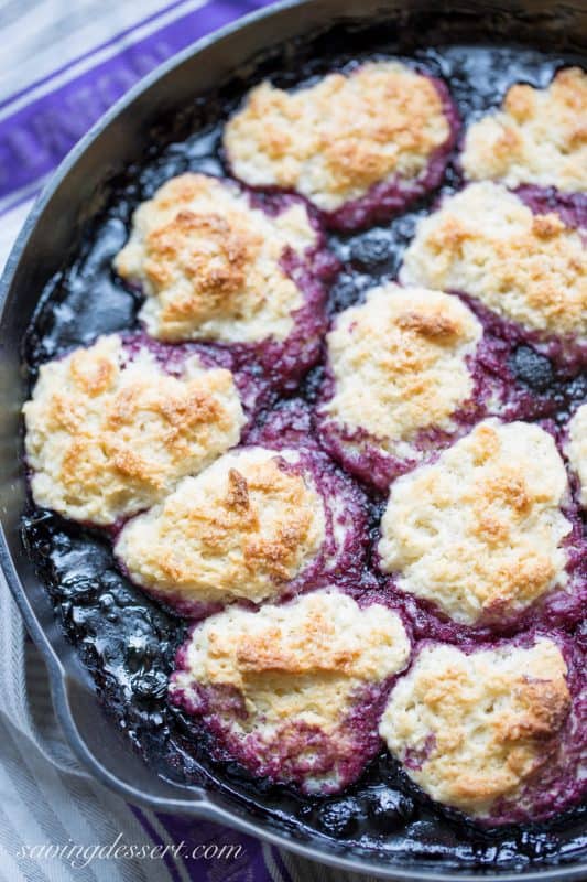 A closeup of a black raspberry biscuit topped cobbler in a cast iron skillet