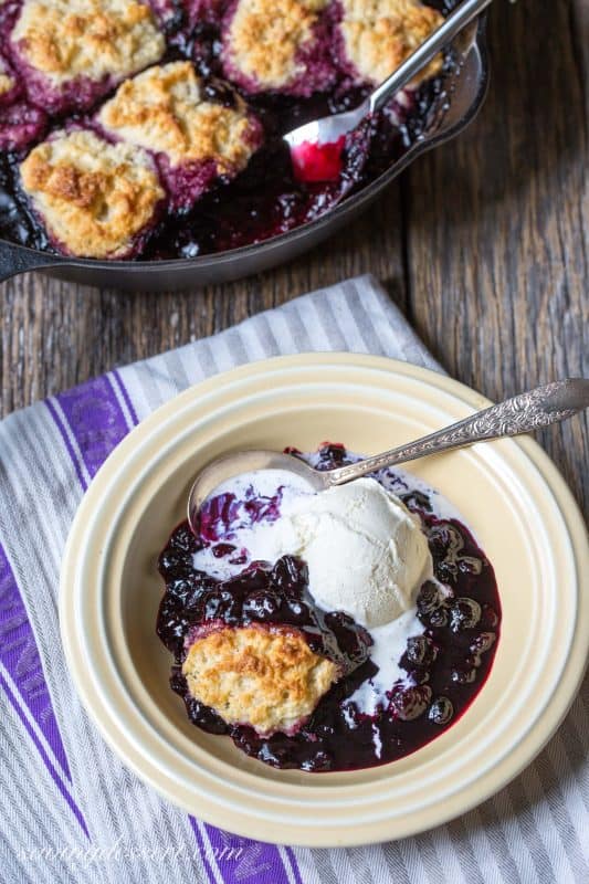 Black Raspberry Cobbler in a bowl with a scoop of vanilla ice cream melting on top