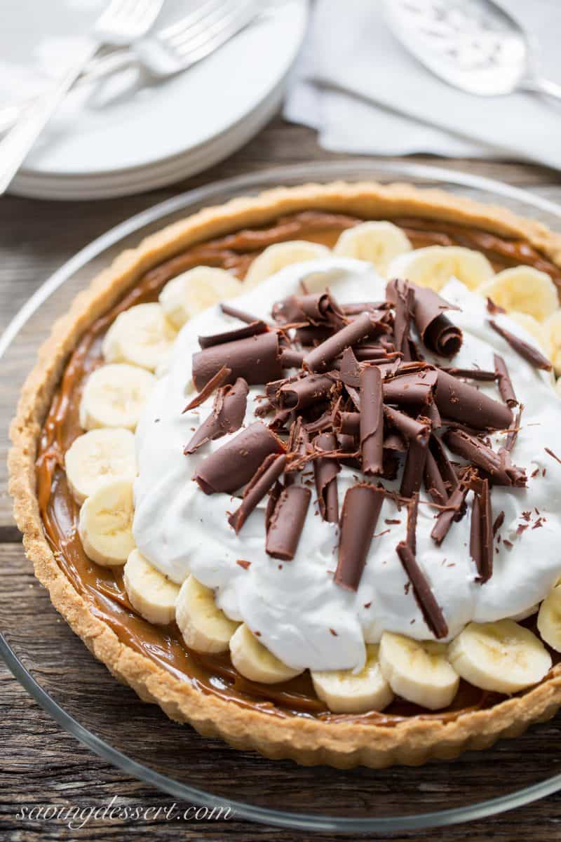 A pretty banoffee pie with silky caramel, fresh sliced bananas, whipped cream and chocolate curls