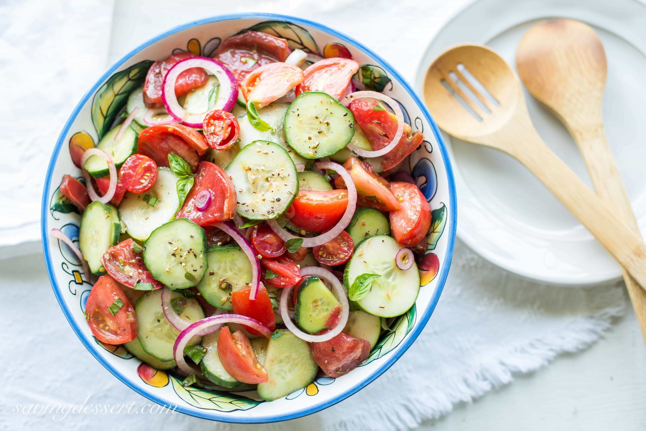 An overhead view of a bowl of tomatoes, cucumber and onion salad.