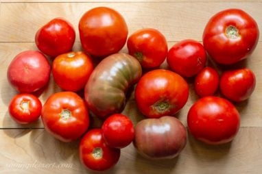 A collection of fresh home grown tomatoes on a cutting board.