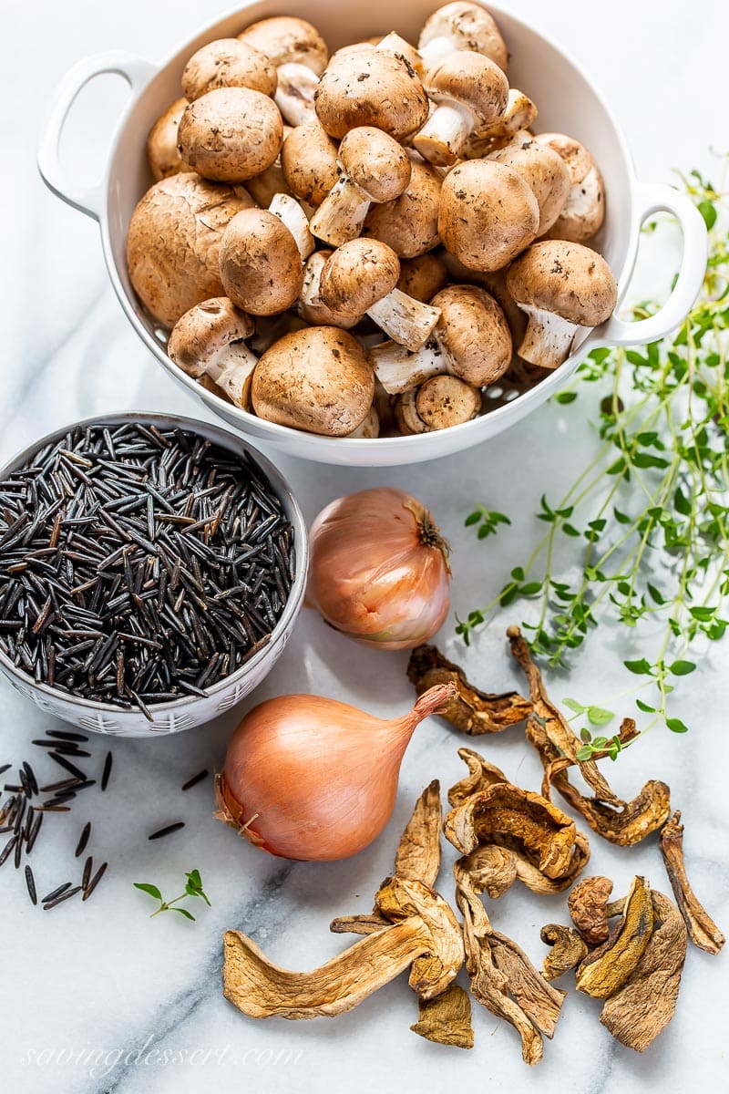 Fresh mushrooms, wild rice, shallots and thyme sprigs on marble