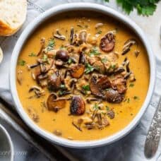 A bowl of wild rice mushroom soup served with bread and parsley butter