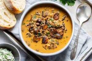 A bowl of wild rice mushroom soup served with bread and parsley butter