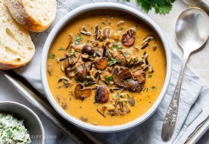 A bowl of wild rice mushroom soup served with bread and parsley butter