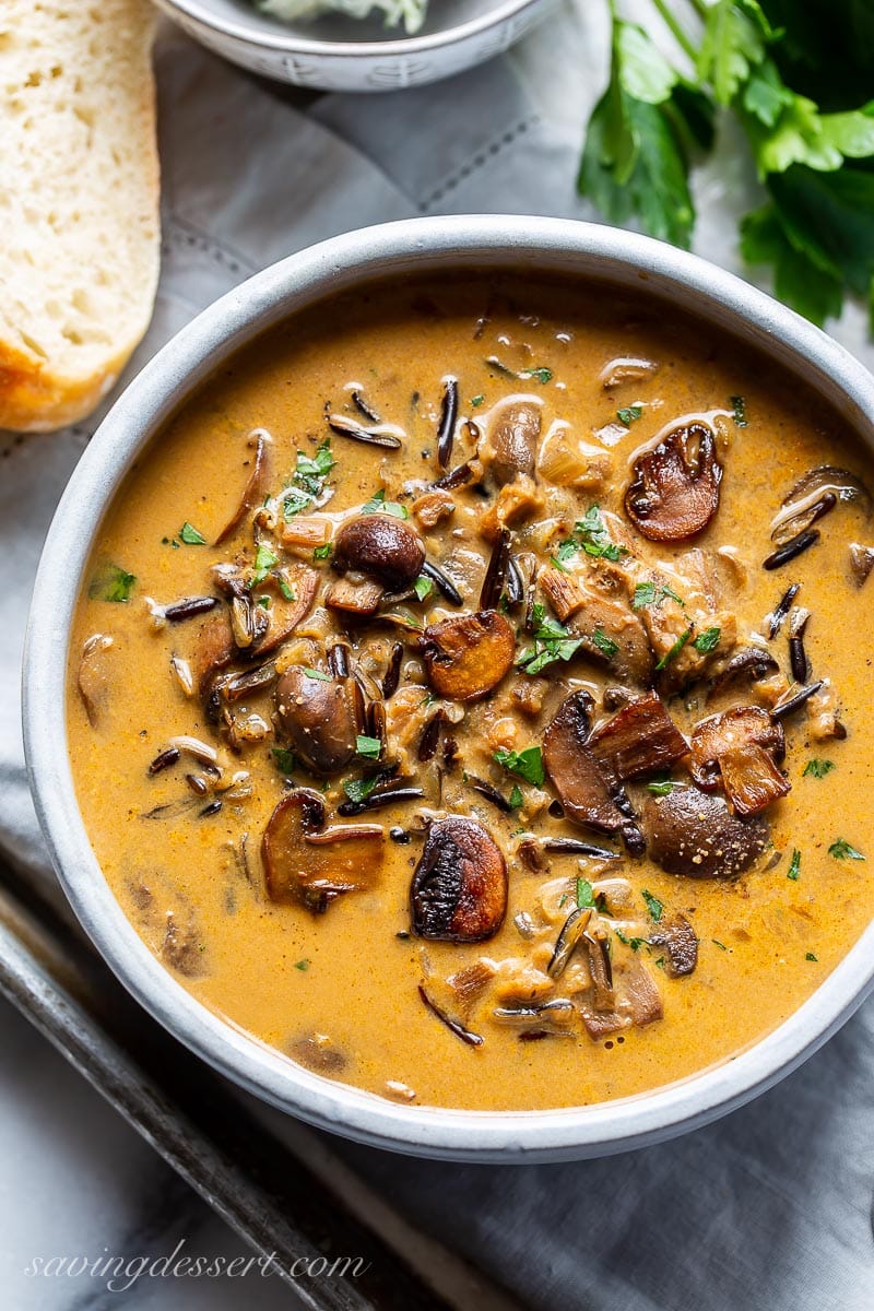 An overhead of a bowl of mushroom soup garnished with parsley and fresh ground black pepper