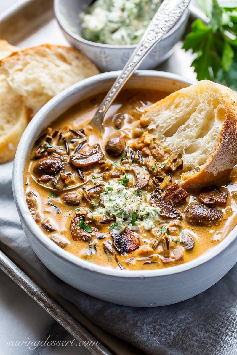 Bread dipped into a hearty bowl of wild rice soup with mushrooms