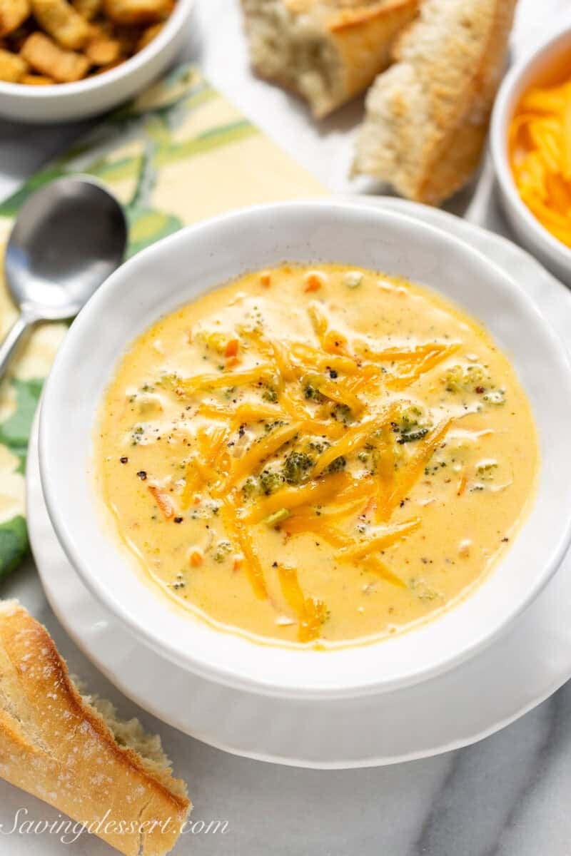 An overhead shot of a bowl of broccoli cheddar soup topped with additional shredded cheddar cheese.