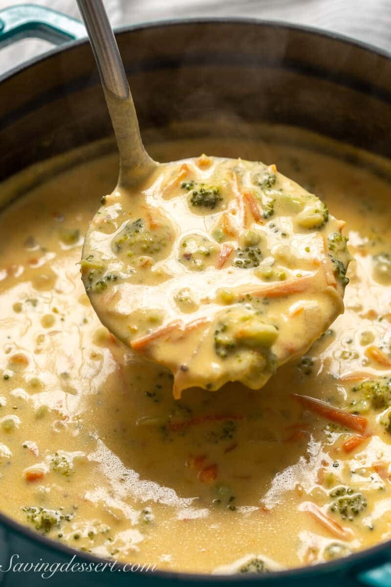 A ladle of broccoli soup over a pot.