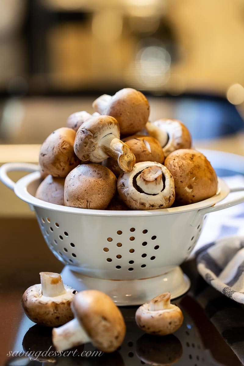 A strainer filled with fresh mushrooms