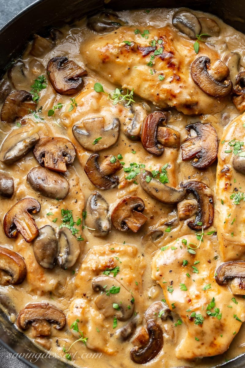 A skillet with chicken breasts covered in a mushroom wine and herb gravy