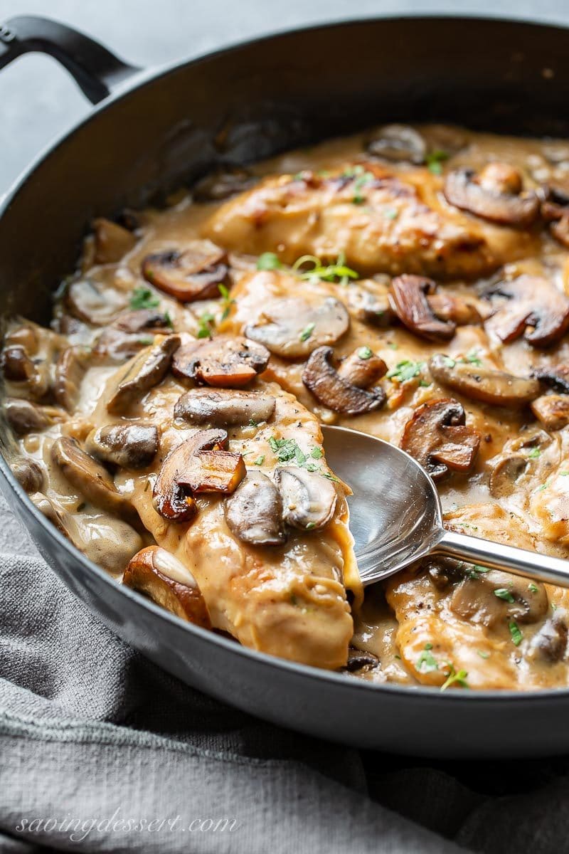 A skillet filled with chicken cutlets in a mushroom wine sauce