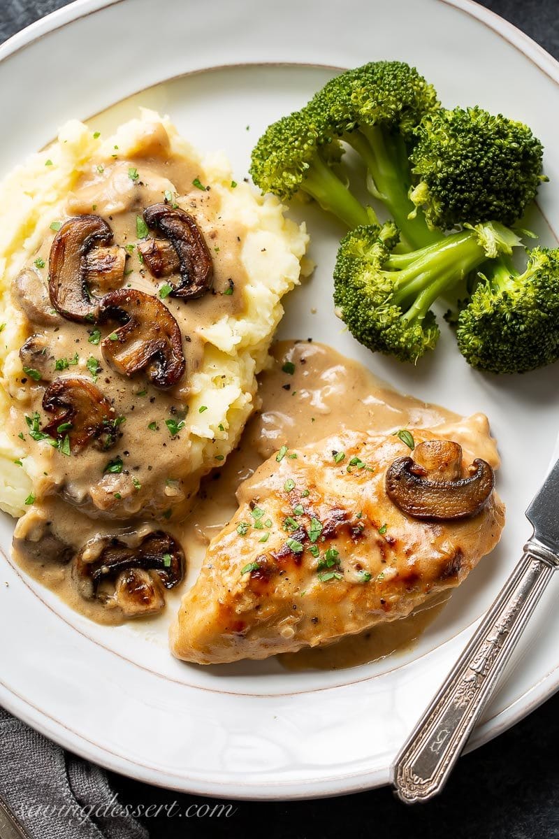 A plate with chicken in mushroom wine sauce with broccoli and mashed potatoes