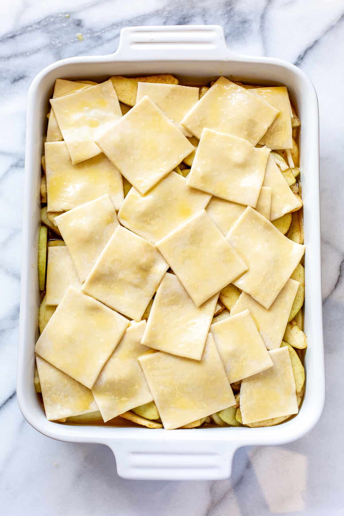 Pastry squares brushed with a beaten egg layered over apple filling