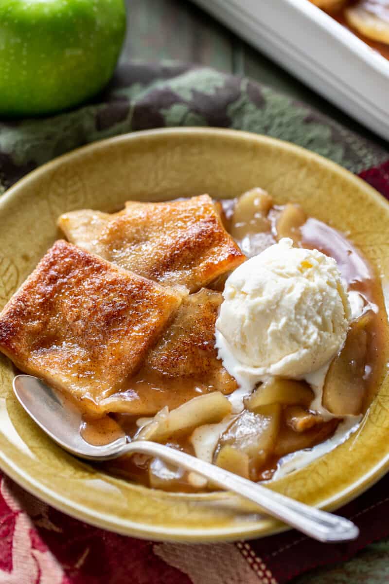 A bowl of apple pandowdy with a golden brown crust topped with a scoop of ice cream