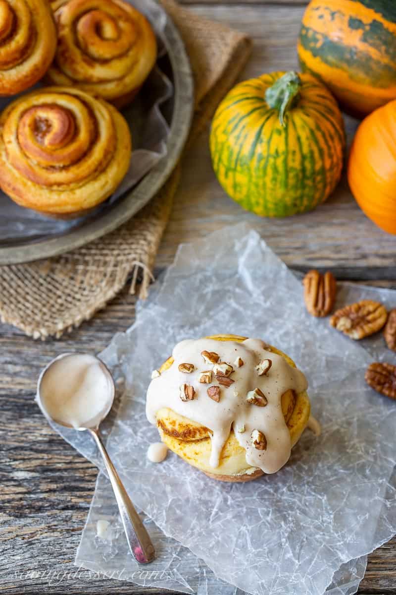 A swirled cinnamon roll topped with cinnamon icing and chopped nuts
