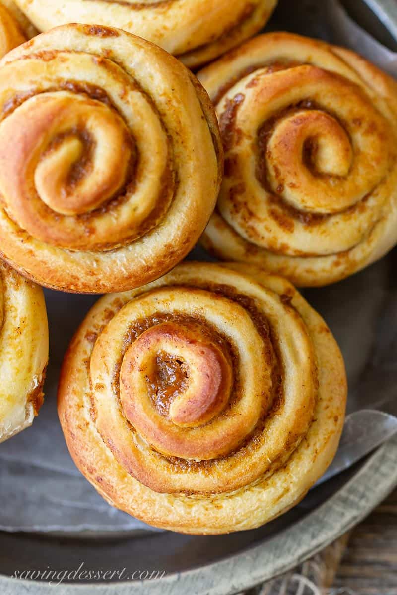 A close up of swirled pumpkin butter cinnamon rolls in a pan