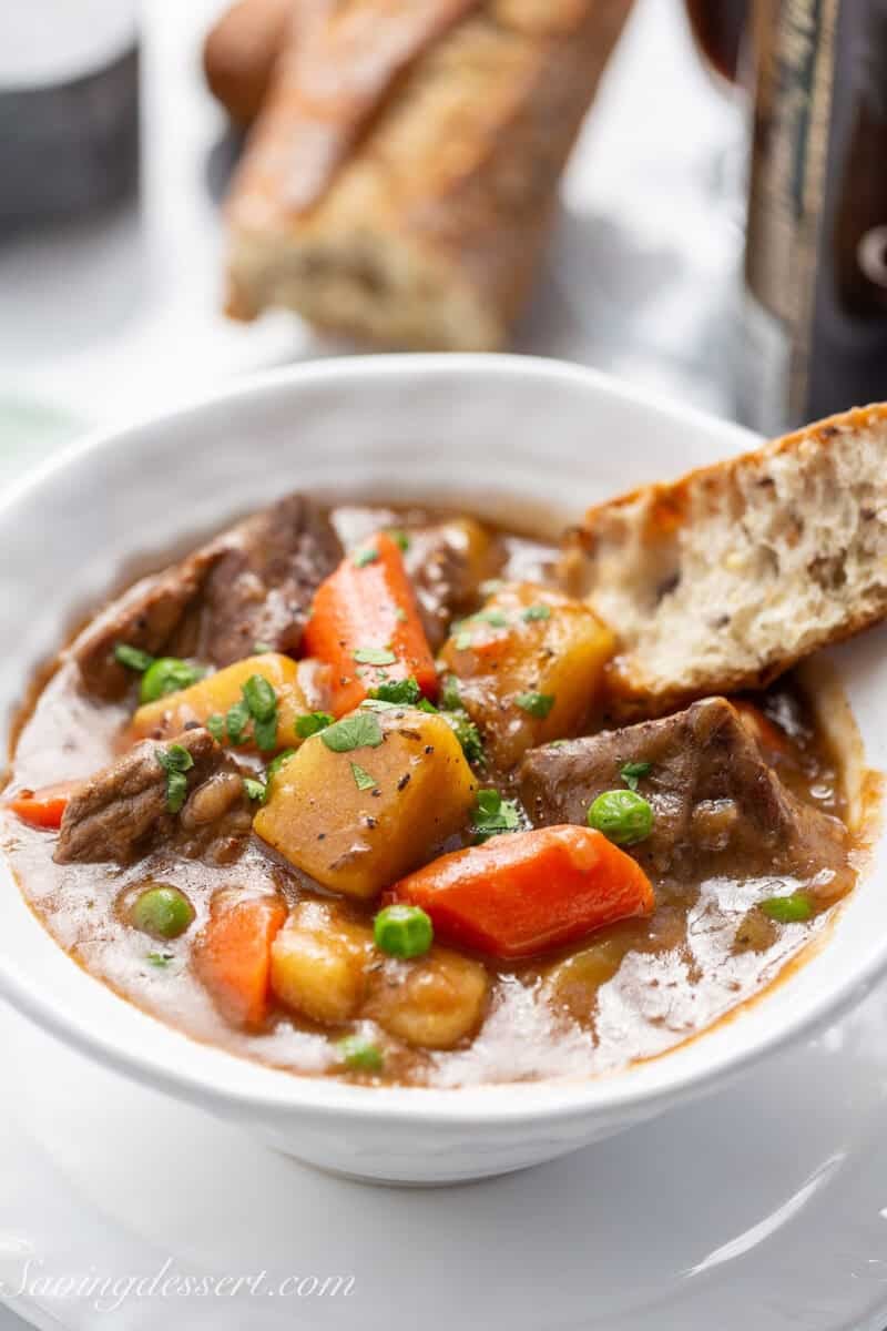Guinness Beef Stew in a bowl with a piece of crusty bread in the broth.