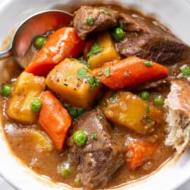 A bowl of Guinness Beef Stew with a spoon and hunk of crusty bread.