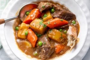 A bowl of Guinness Beef Stew with a spoon and hunk of crusty bread.
