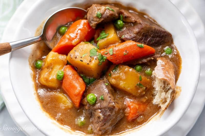 A bowl of Guinness Beef Stew with a spoon and hunk of crusty bread.