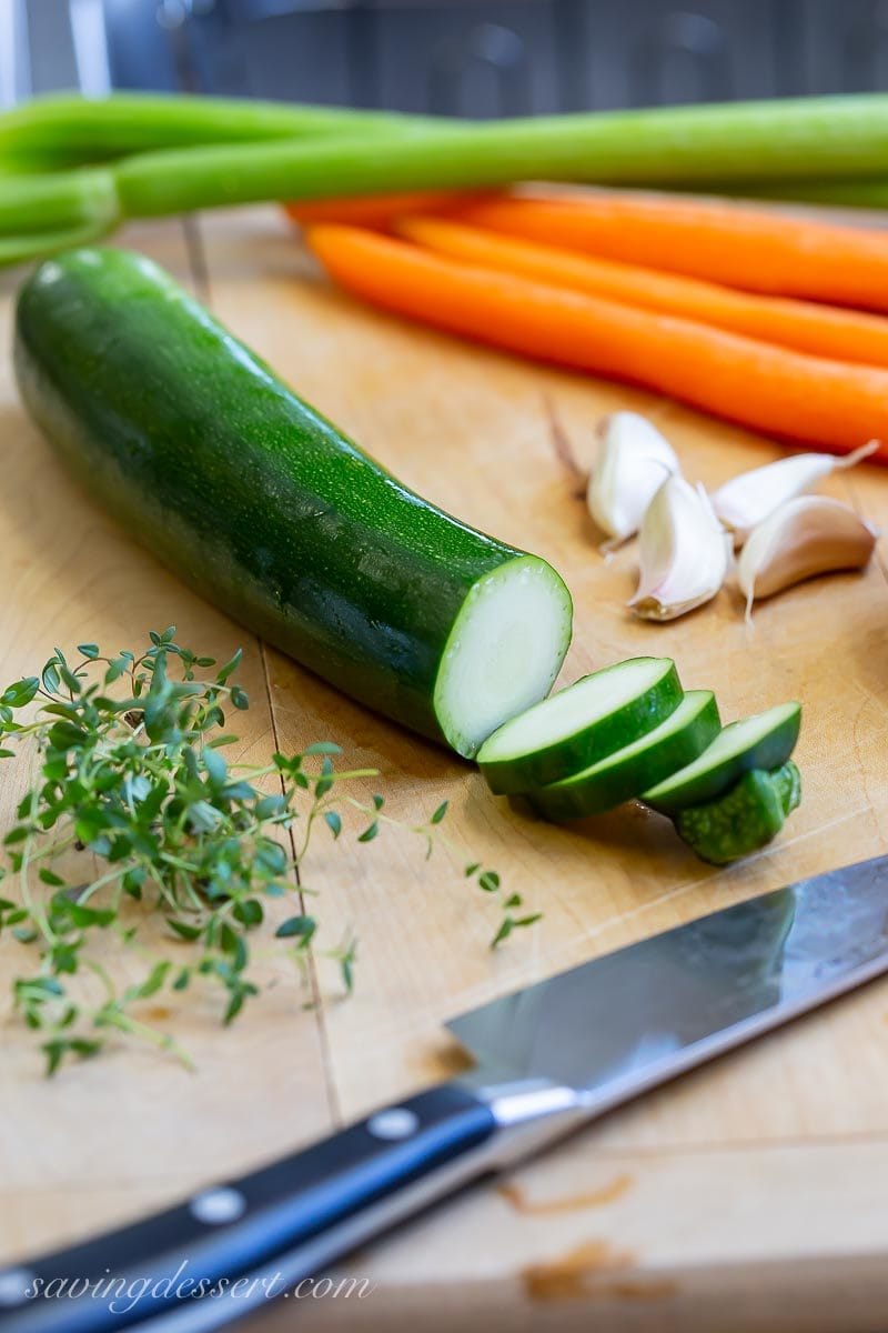 zucchini, carrots, garlic and celery on a cutting board with fresh thyme