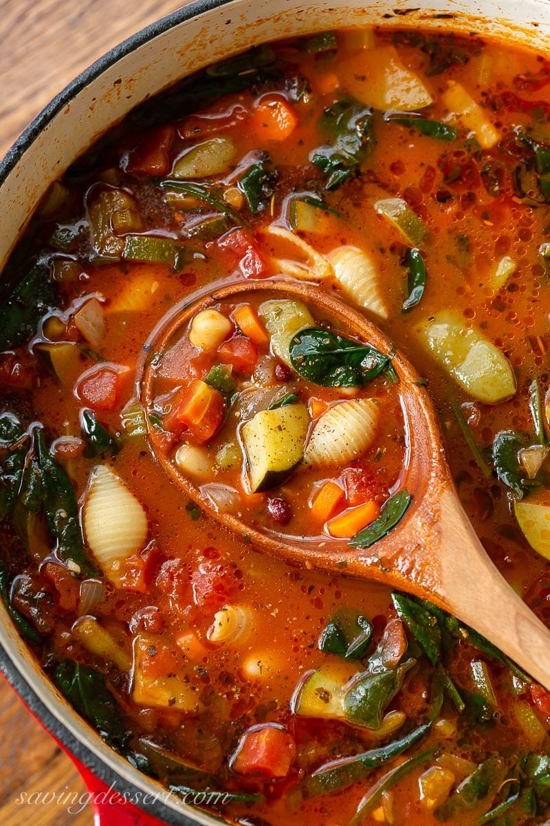 A pot of vegetable soup with shell shaped pasta in a tomato broth