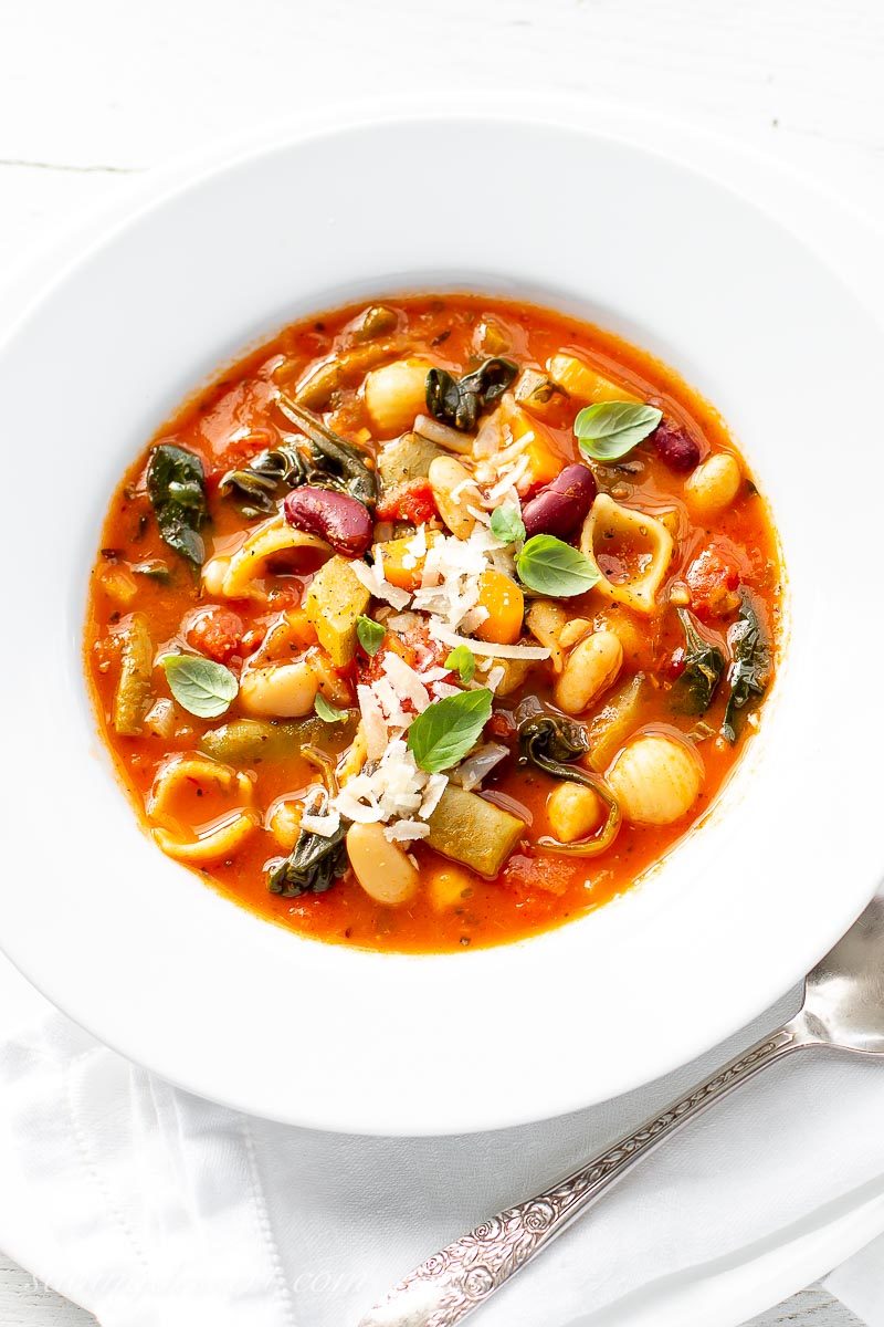 Classic Minestrone Soup garnished with Parmesan and basil leaves