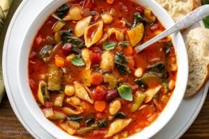 A close up of a bowl of Minestrone Soup with spinach and fresh basil leaves