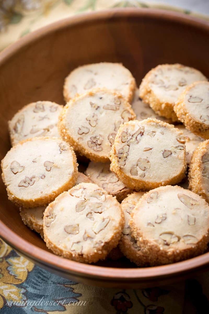 A wooden bowl filled with pecan sandies with pecans