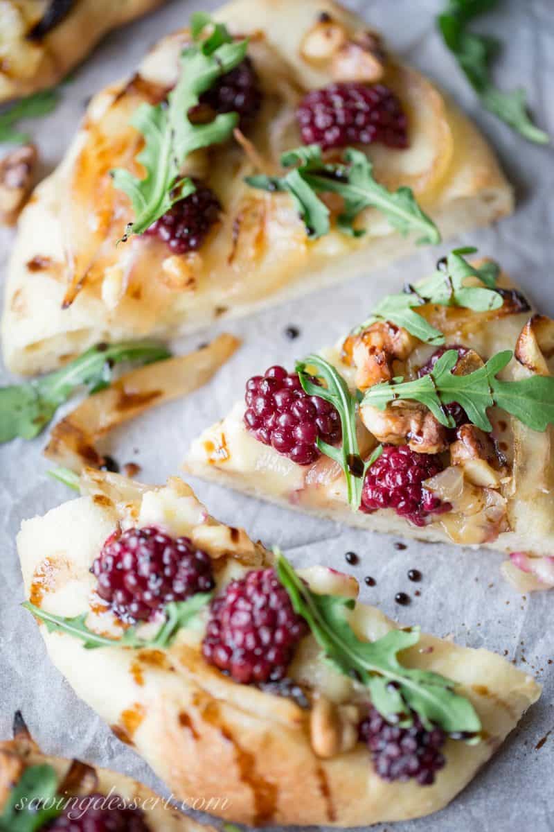 Blackberries and brie cheese made into a mini pizza with caramelized onions, arugula and a drizzle of balsamic