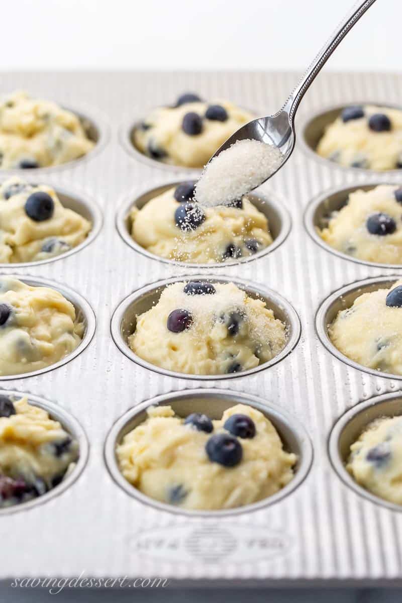 Unbaked muffins being sprinkled with coarse sugar