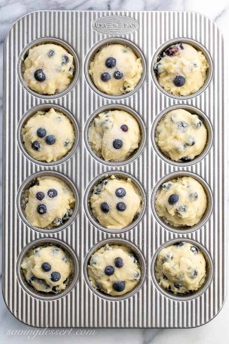 A muffin tin filled with blueberry muffin batter