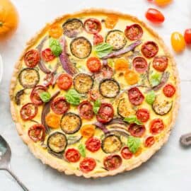 Overhead view of a vegetable quiche with tomatoes fresh basil and onions