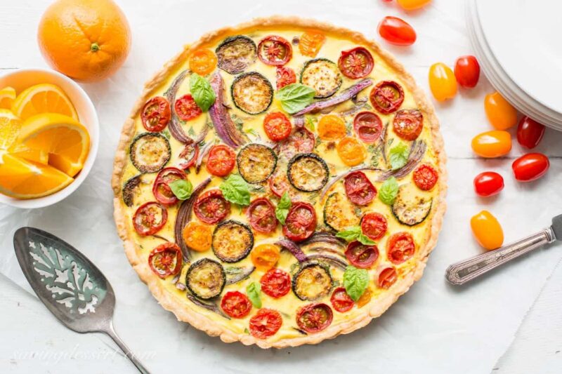 Overhead view of a vegetable quiche with tomatoes fresh basil and onions