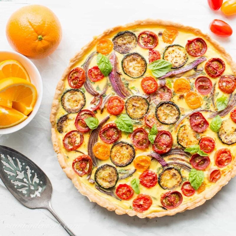 A Farmers Market Quiche loaded with fresh tomatoes, herbs, onions and zucchini. Served with fresh sliced oranges