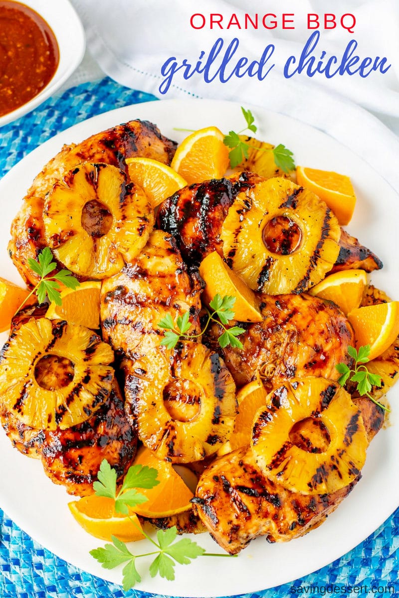 A platter of grilled Orange BBQ Chicken with pineapple and orange wedges