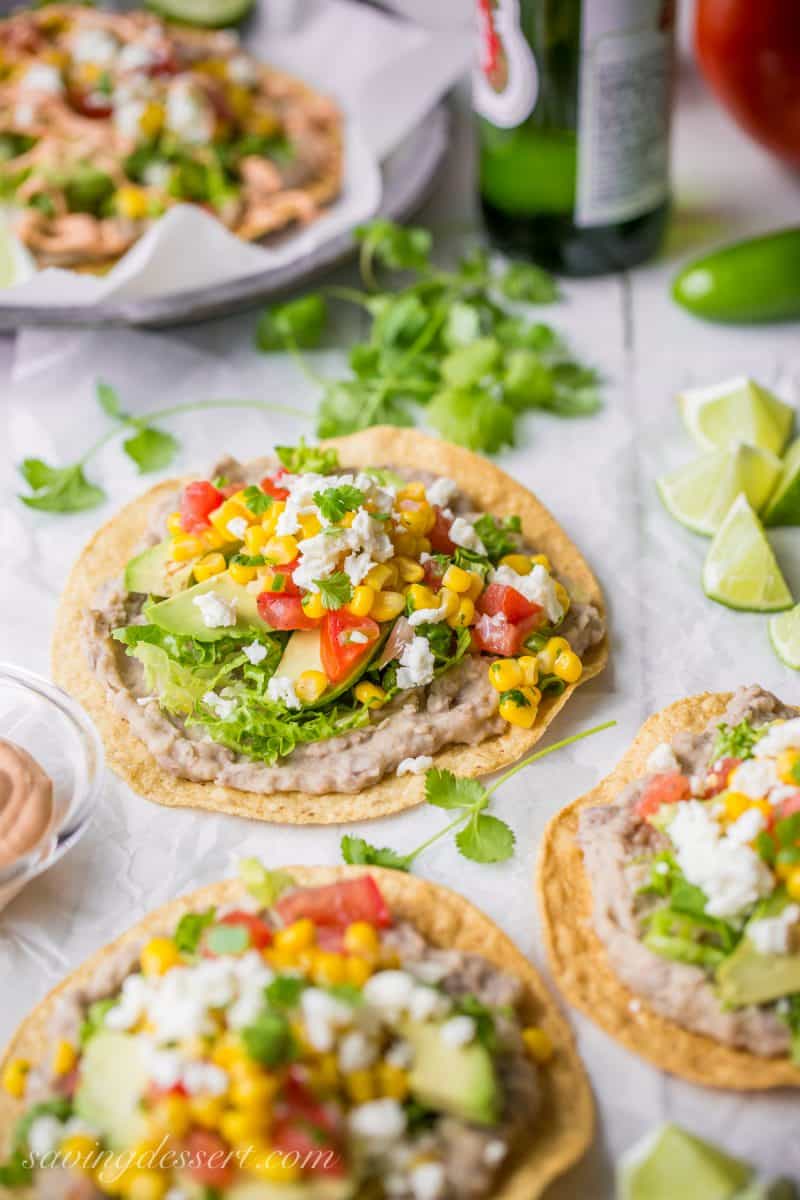 Homemade refried beans on tostadas, topped with tomatoes, cheese, avocado and corn