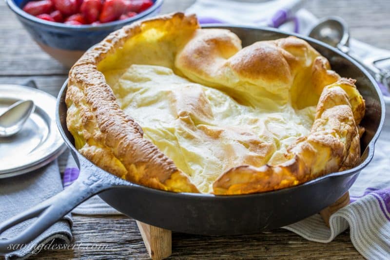 A skillet with a puffed up german pancake just out of the oven