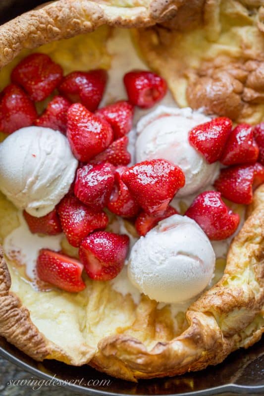 A close up of strawberries and ice cream in a fresh baked German pancake
