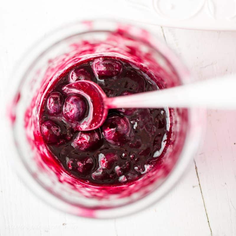 A jar of homemade blueberry sauce with a spoon