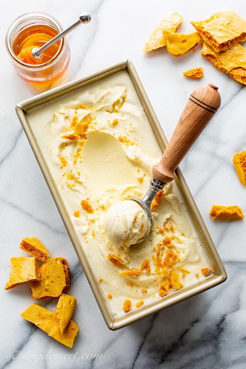 An overhead shot of a pan of buttermilk honey ice cream scooped into a ball