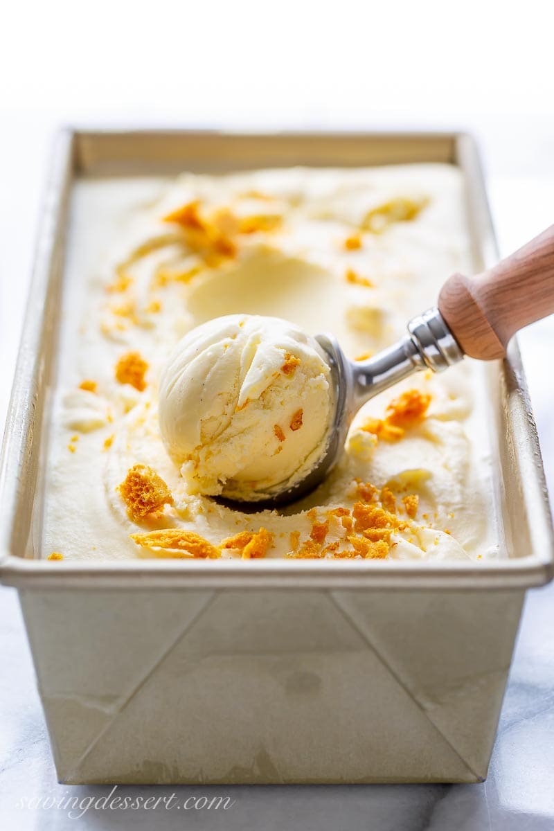 A loaf pan filled with honey ice cream topped with crushed honeycomb candy
