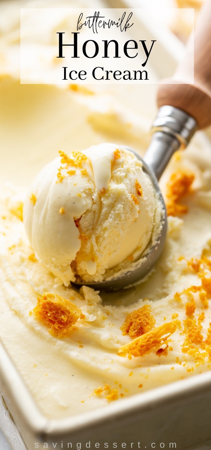 A pan with homemade honey ice cream topped with crushed honeycomb candy with an ice cream scoop