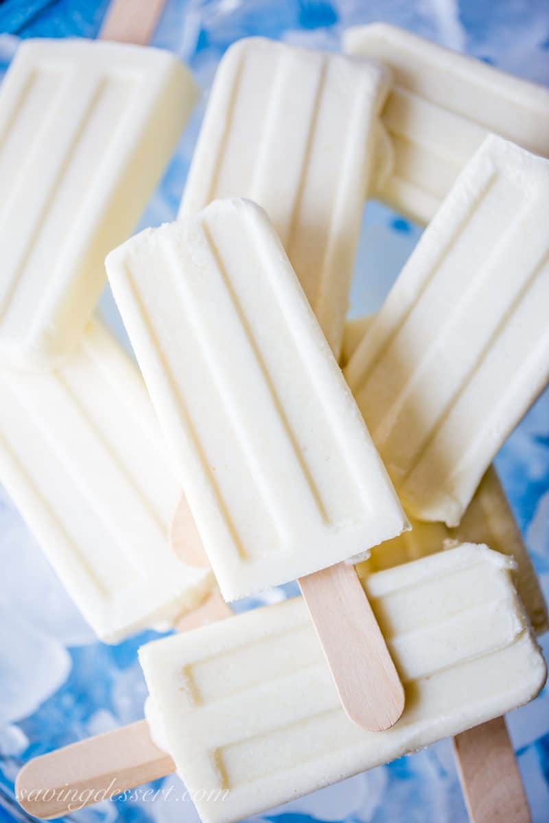 coconut pineapple popsicles stacked over a bowl of chopped ice