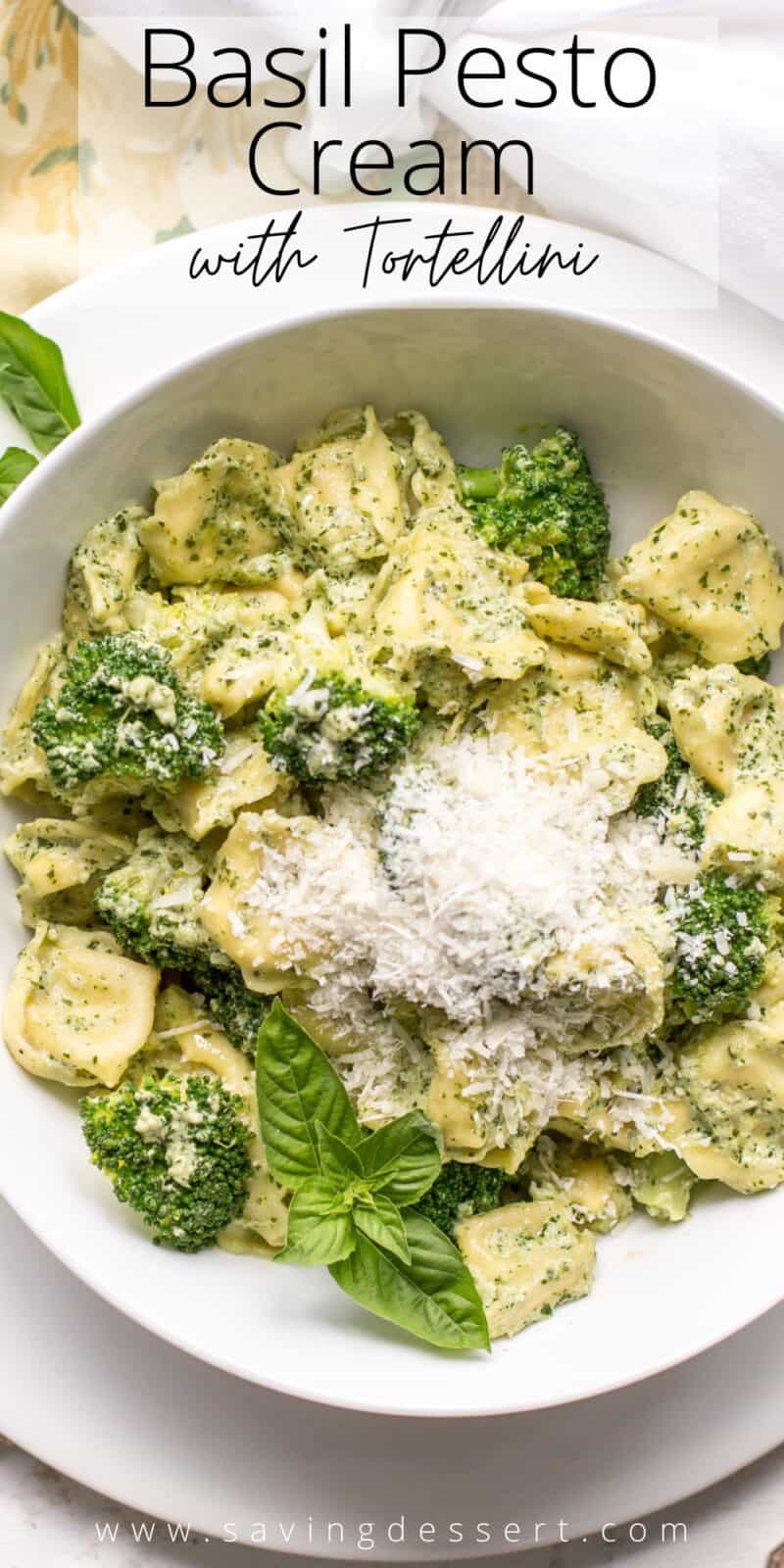 A bowl of tortellini covered in a basil cream sauce and Parmesan cheese