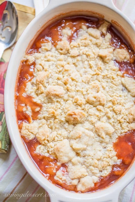 A casserole dish filled with a peach dessert topped with a crumbled dough