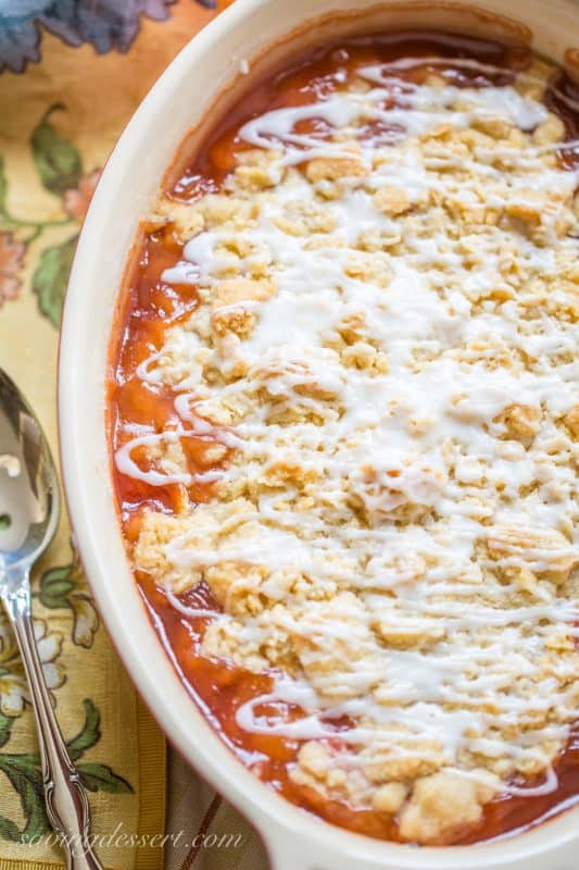 A peach crumble in a casserole dish topped with a drizzled icing